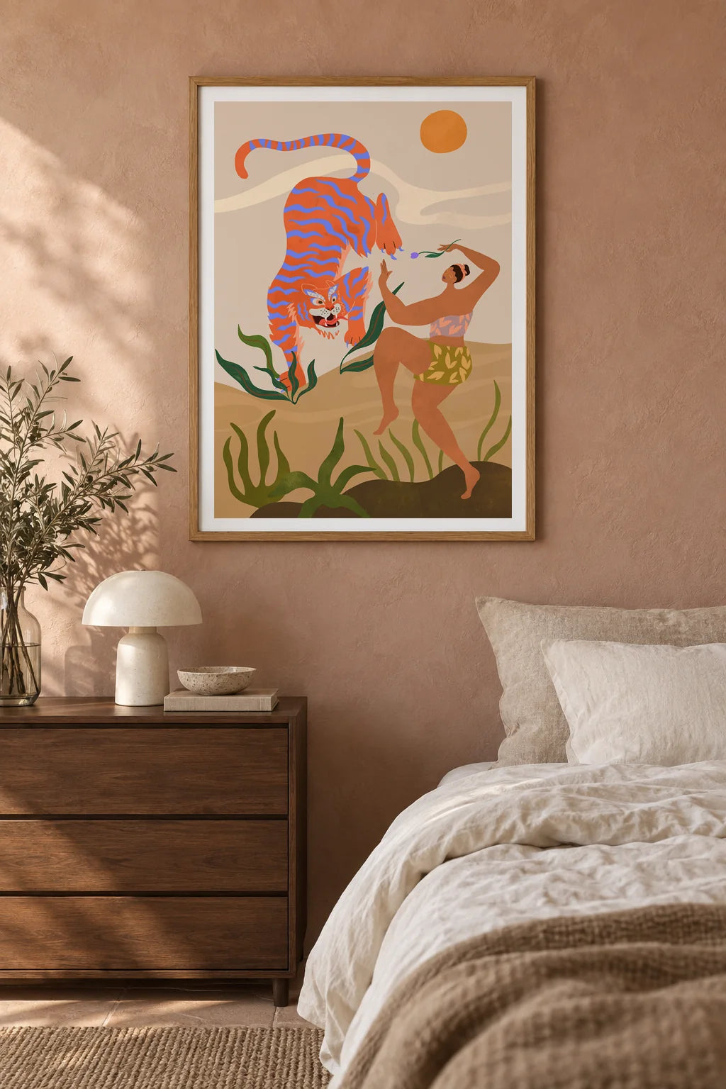 Dance With Me by Arty Guava – orange tiger with violet stripes beside a dancing woman and green leaves. Oak-framed print styled above a walnut bedside chest in a warm bedroom.
