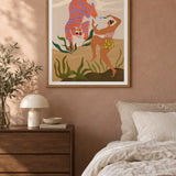 Dance With Me by Arty Guava – orange tiger with violet stripes beside a dancing woman and green leaves. Oak-framed print styled above a walnut bedside chest in a warm bedroom.