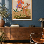 Dance With Me by Arty Guava – orange tiger with violet stripes beside a dancing woman and green leaves. Oak-framed print above a walnut sideboard against a blue living-room wall.