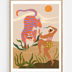 Dance With Me by Arty Guava – orange tiger with violet stripes beside a dancing woman and green leaves. Art print shown in a natural oak frame on a white wall.