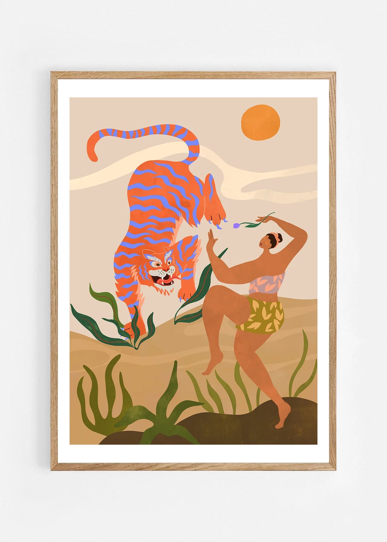Dance With Me by Arty Guava – orange tiger with violet stripes beside a dancing woman and green leaves. Art print shown in a natural oak frame on a white wall.